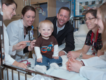 Family-centered rounds at American Family Children's Hospital.  From left: pediatric hospitalist Michelle Kelly, MD; pediatric intern Leslie Riopel, MD; Ayden Hollman and his father Jake; an AFCH pediatric nurse; and senior pediatric resident Jennifer Hartwell, MD.